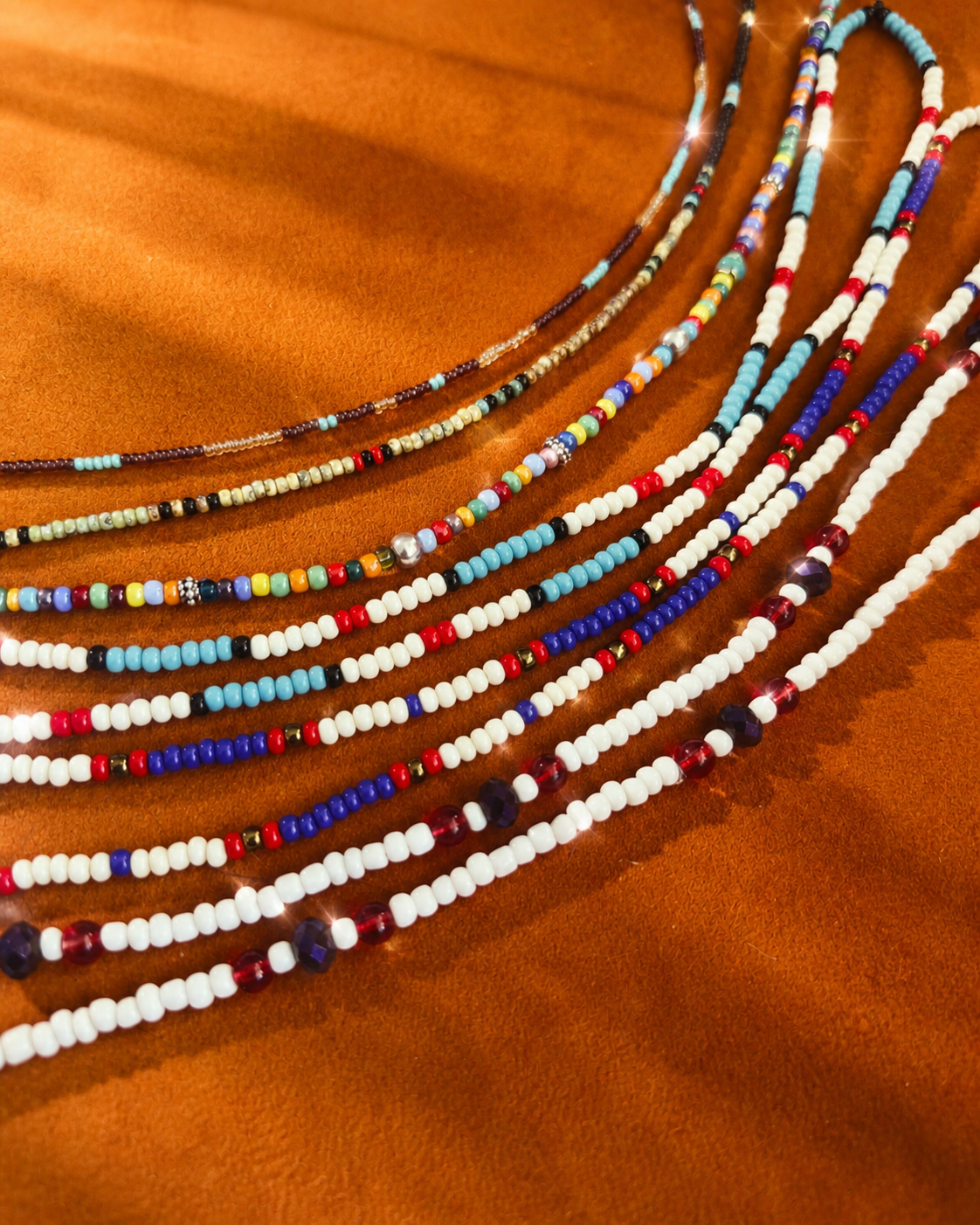 Strands of colorful handcrafted seed-bead necklaces made through The Beading Project.